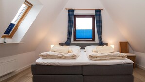 Une chambre avec un grand lit, une fenêtre avec des rideaux et un radiateur.