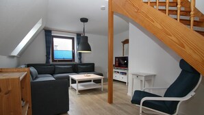 Un salon moderne comprenant un canapé, une table basse, un fauteuil et un escalier.