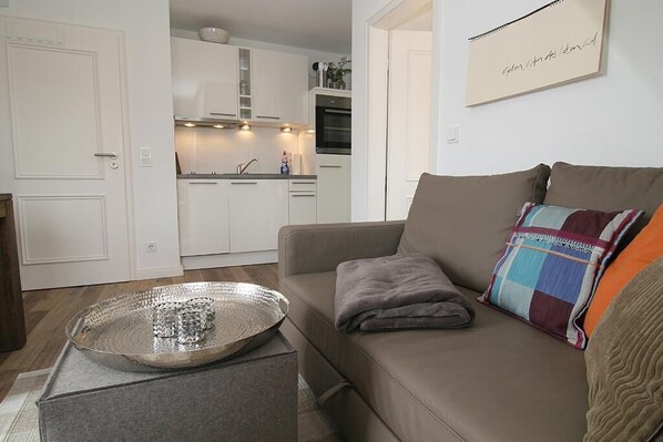 Un salon avec un canapé, une petite table et une cuisine en arrière-plan.