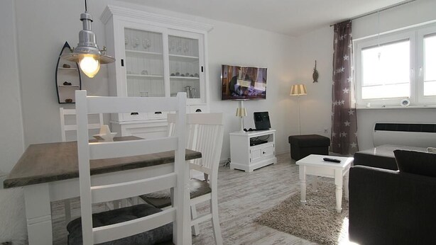 A modern living room with a bunk bed, white furniture, a flat-screen TV, and a window with curtains. - Wonderful vacation apartment, suitable for 4 people (Hörnum auf Sylt)