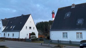 Een kustdorp met witte huizen, een opvallend rood-wit gestreept vuurtoren en een heldere lucht.