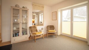 Een kamer met een kast, twee stoelen, een raam en een spiegel.