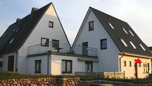 A row of white houses with sloped roofs and balconies. - This 3-room vacation apartment is spacious and on the ground floor (Hörnum auf Sylt)