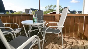 An outdoor patio with a round table and four chairs, a bottle of water, and a chalkboard. - Directly on the beach with a view of the sea (Hörnum auf Sylt)