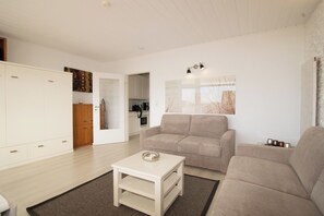 Una sala moderna con un sofá, una mesa de centro y una cocina al fondo.