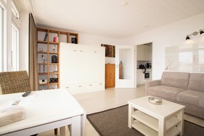 Een moderne woonkamer met een witte bank, een witte salontafel en een boekenkast.