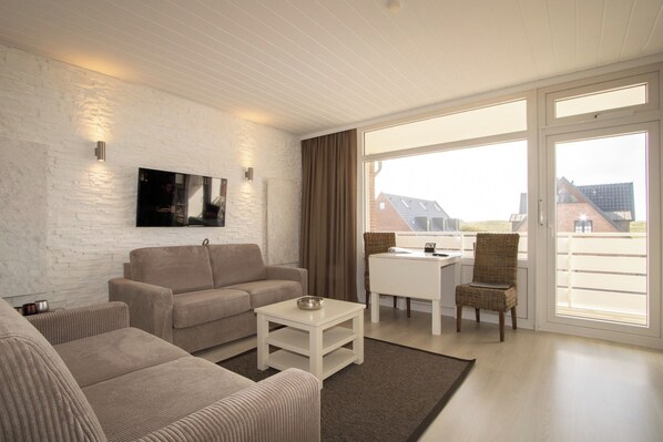 A modern living room with a sofa, a coffee table, and a TV mounted on a white brick wall.