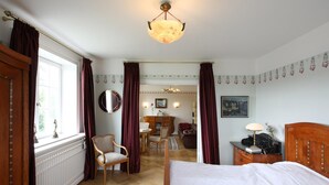 Ein Schlafzimmer mit Bett, Sessel, Schreibtisch und Essecke.