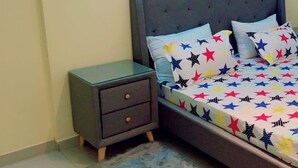 A bedroom with a bed, a nightstand, and a fluffy rug.
