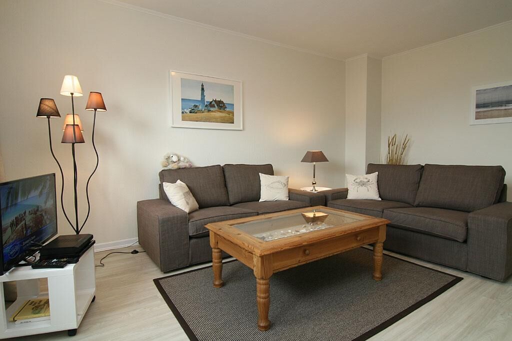 Un salon comprenant un canapé, une table basse, un téléviseur et des lampes sur pied.