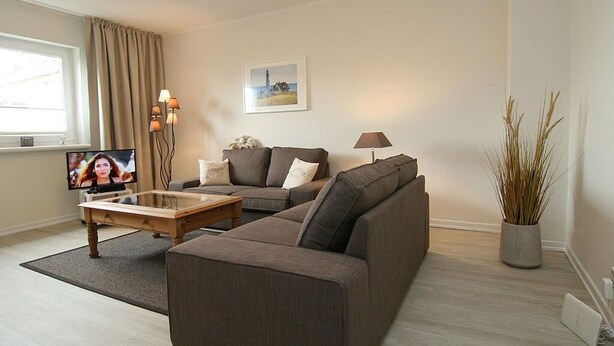 A living room with a sofa, a coffee table, a TV, and a lamp.