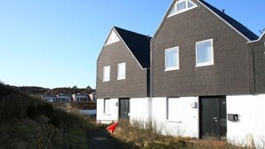 A modern two-story house with a grey roof and white walls, featuring a pathway leading to the entrance. - Attractive vacation apartment in an absolutely quiet location in the Hörnum dunes (Hörnum auf Sylt)