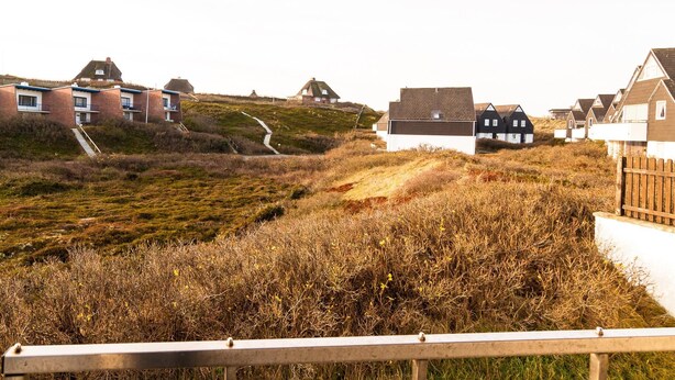 A coastal residential area with houses on a hillside, a pathway leading up, and a wooden fence in the foreground. - Attractive vacation apartment in an absolutely quiet location in the Hörnum dunes (Hörnum auf Sylt)