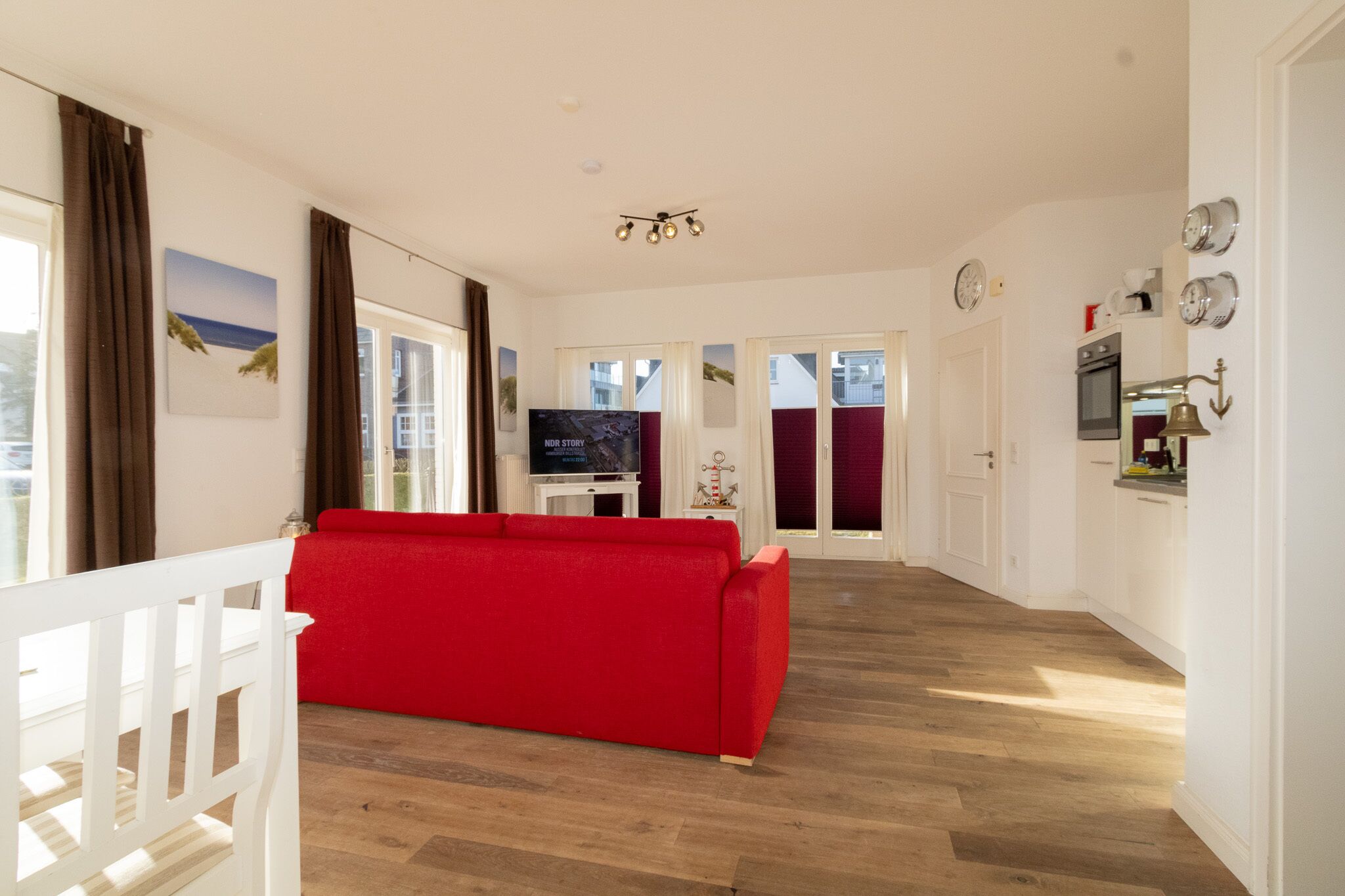 Un salon moderne avec un canapé rouge, un plancher en bois et un téléviseur.