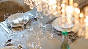 A dining table set with clear glassware, plates, and cutlery, reflecting light from a chandelier. - Spacious golf house with sauna, fireplace and terrace - 200 m to the beach in Hörnum (Hörnum auf Sylt)