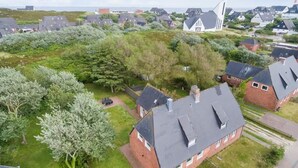 An aerial view of a residential area with houses, a church, and a grassy field. - Spacious golf house with sauna, fireplace and terrace - 200 m to the beach in Hörnum (Hörnum auf Sylt)