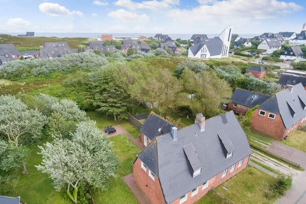 An aerial view of a residential area with houses, a church, and a grassy field.