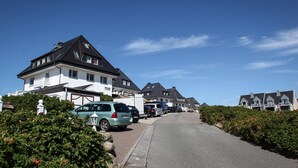 A residential street with houses, parked cars, and a clear blue sky. - The Leuchtfeuer apartment is located in the Atair house in Hörnum.... (Hörnum auf Sylt)