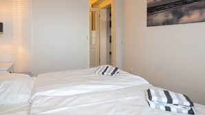 A bedroom with a bed, a painting, and a door leading to another room. - The Leuchtfeuer apartment is located in the Atair house in Hörnum.... (Hörnum auf Sylt)
