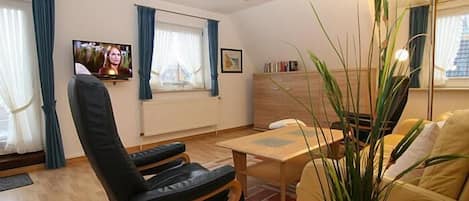 A living room with a sofa, a coffee table, a TV, and a plant.