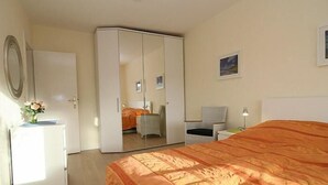 Een slaapkamer met een bed, een kledingkast, een bureau en een stoel.