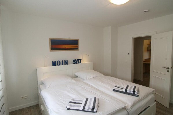 A hotel room with two beds, a painting on the wall, and a sign above the beds.