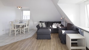Moderni loft-tyylinen asunto, jossa on ruokailutila, harmaa sohvaryhmä ja pieni valkoinen pöytä.