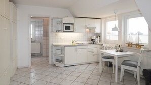 Eine moderne Küche mit weißen Schränken, einer Mikrowelle und einem Essbereich mit Tisch und Stühlen.