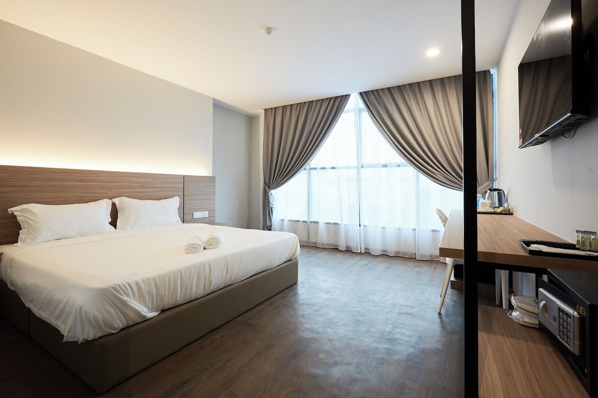Ein Hotelzimmer mit einem großen Bett, einem Schreibtisch mit Computer und einem Flachbildfernseher.