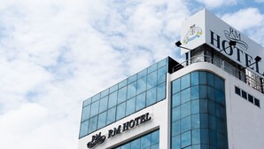 Un edificio de hotel con fachada de vidrio moderna y un cartel que dice "RM HOTEL".