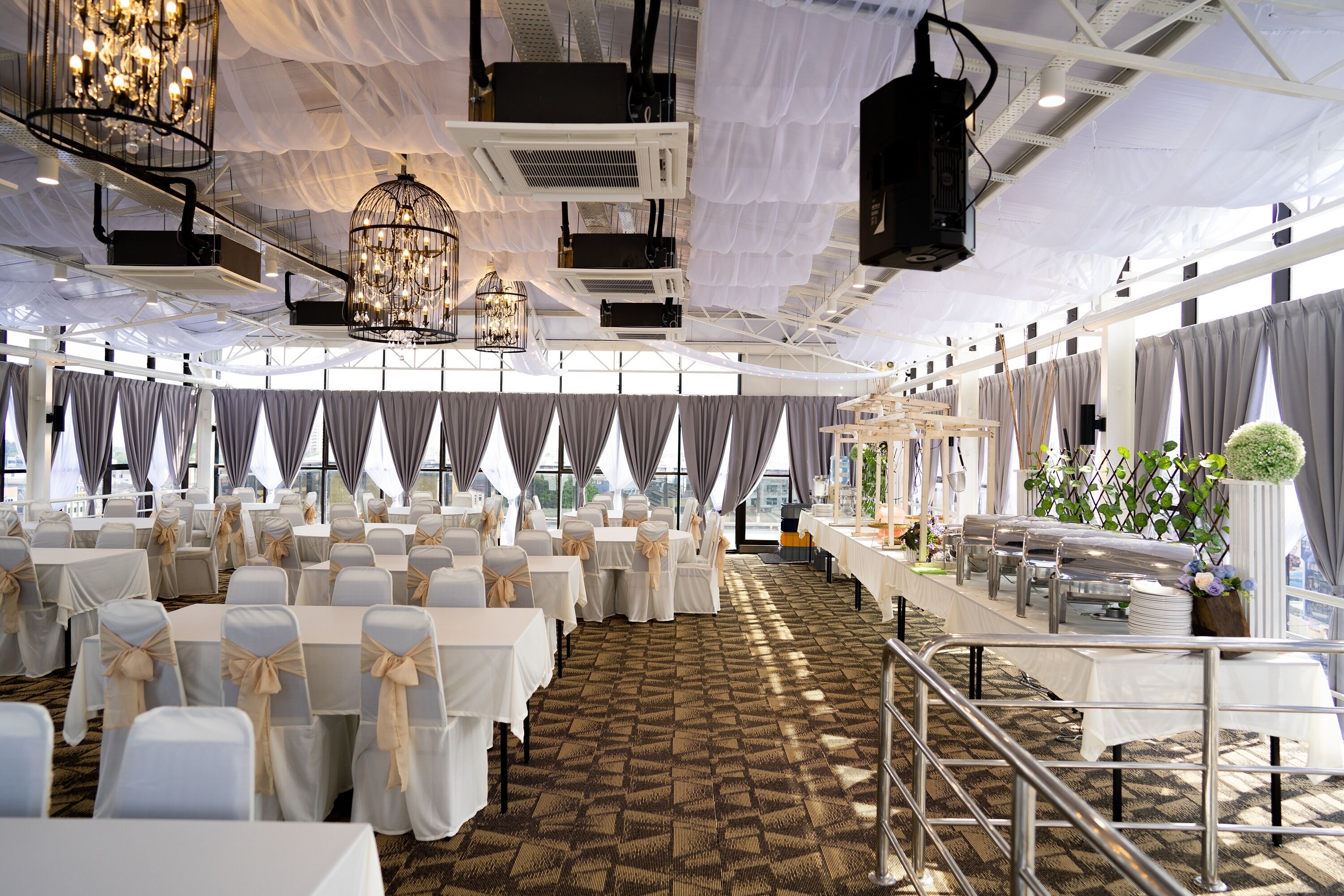 A banquet hall with tables set for events, chandeliers, and a patterned carpet.