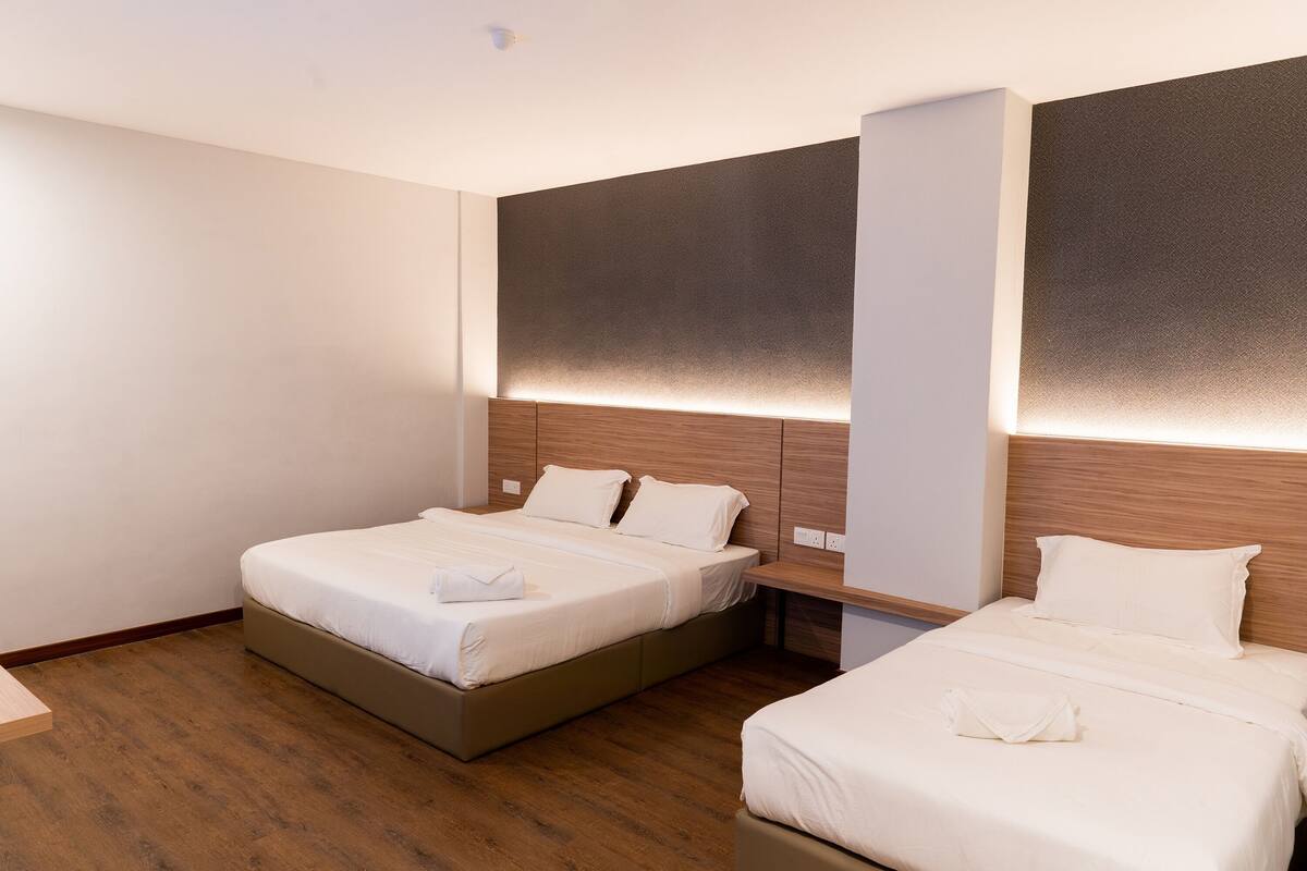 Ein Hotelzimmer mit zwei Betten, Holzboden und einem modernen Kopfteil mit integrierter Beleuchtung.