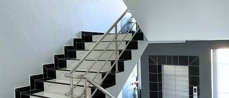 A modern staircase with black and white marble steps and a metal railing.