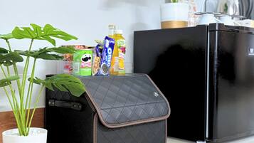 A kitchen area with a black refrigerator, a black suitcase with a quilted cover, and a potted plant.
