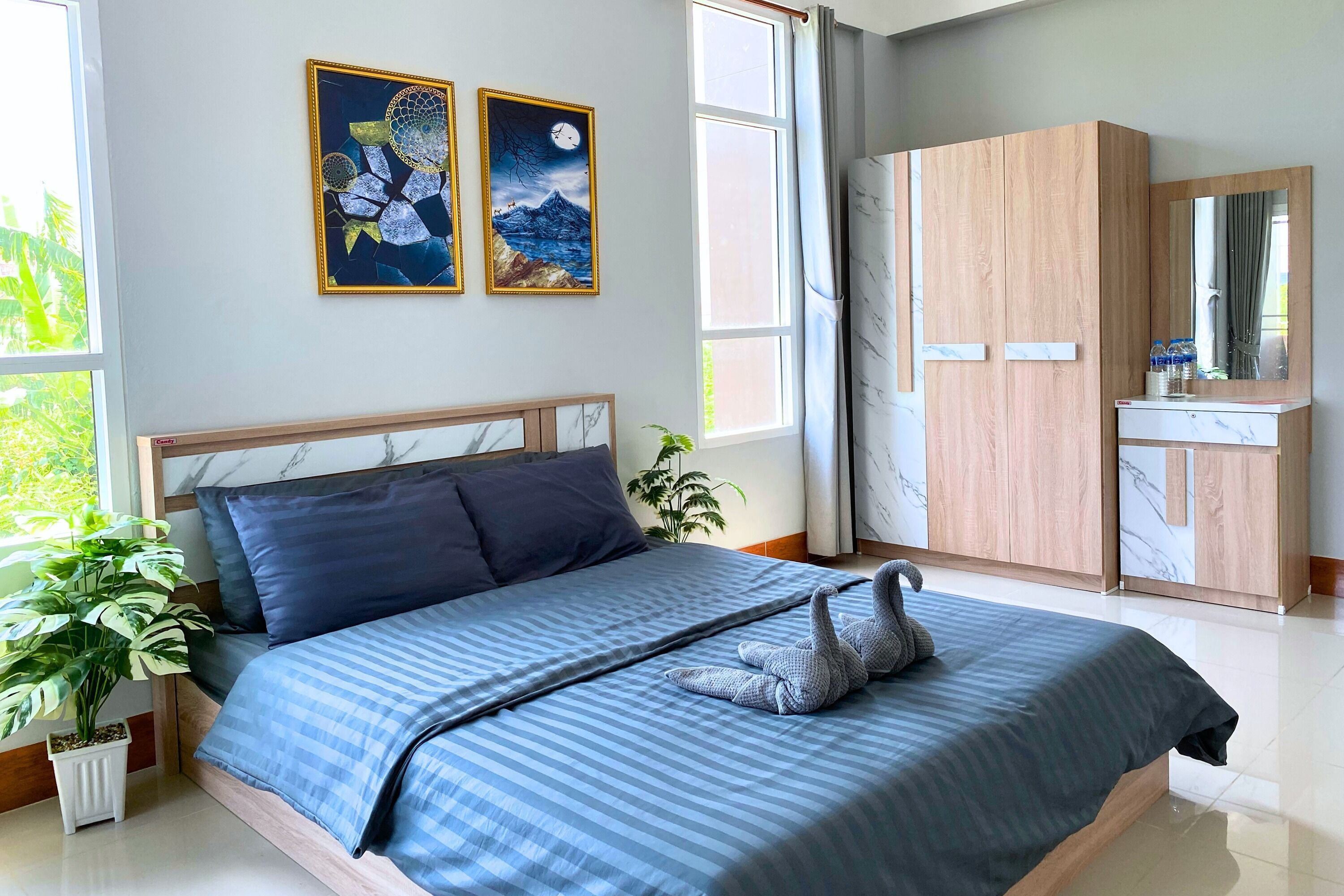A modern bedroom with a bed, a nightstand, a potted plant, and a wardrobe.