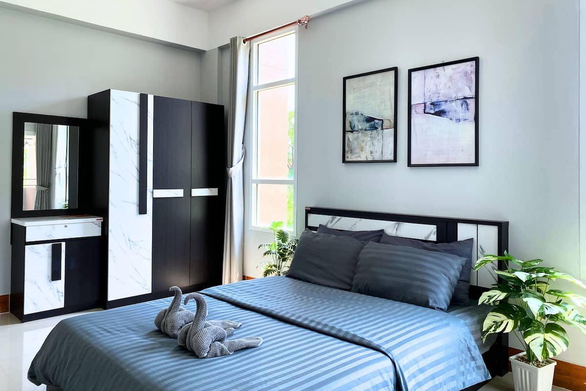Ein Schlafzimmer mit einem Bett, einem Kleiderschrank, einer Kommode und zwei gerahmten Kunstwerken an der Wand.