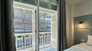 A hotel room with a balcony, a bed, and a nightstand. - Forgotten Hostel Silom (Bangkok)