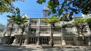 A historic building with a grand entrance, multiple balconies, and a prominent sign reading "FROGOTTEN". - Forgotten Hostel Silom (Bangkok)