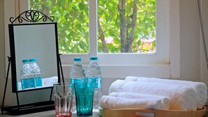 A room with a window, a mirror, a tray with towels, and water bottles. - R 17 Living Hotel (Bangkok)