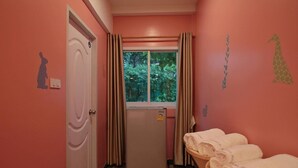 A room with pink walls, a white door, a window with curtains, a refrigerator, and towels on a table. - R 17 Living Hotel (Bangkok)