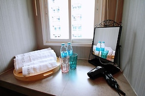 A hotel room with a window, a wooden tray with towels, a mirror, and a hairdryer. - R 17 Living Hotel (Bangkok)