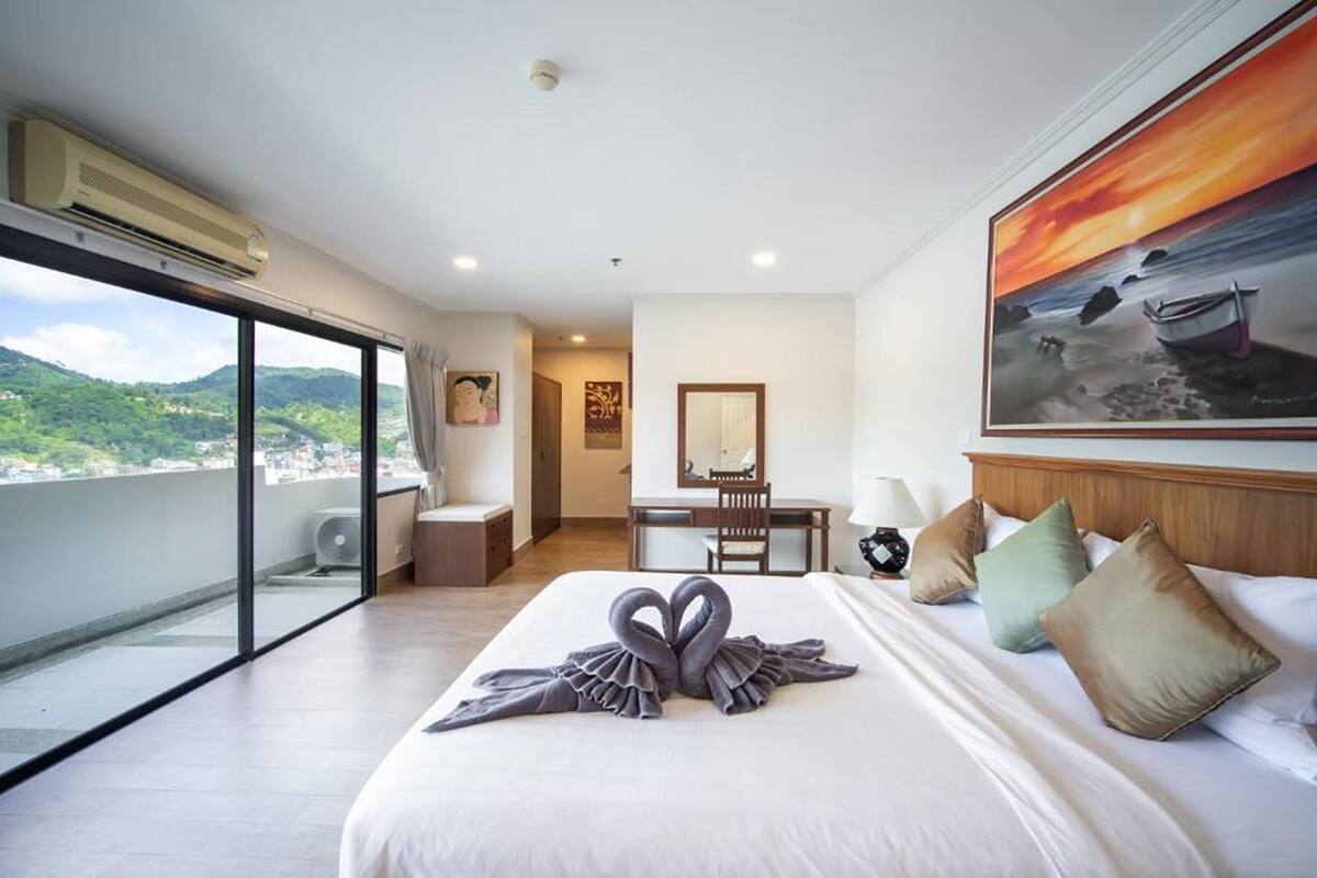 A hotel room with a large bed, a desk, and a view of the city.