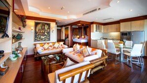 A modern living room with a sofa set, a glass coffee table, and a dining area with a white table and chairs. - Patong Tower Beach Apartment By Seesea (Patong)