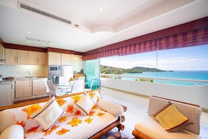 A modern hotel room with a balcony, a kitchen area, and a bed with floral bedding.