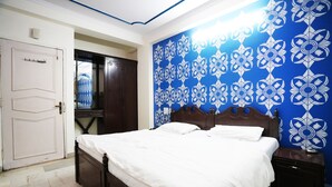 A bedroom with a bed, a wardrobe, and a blue patterned wall. - Hotel Le Sancy (New Delhi)