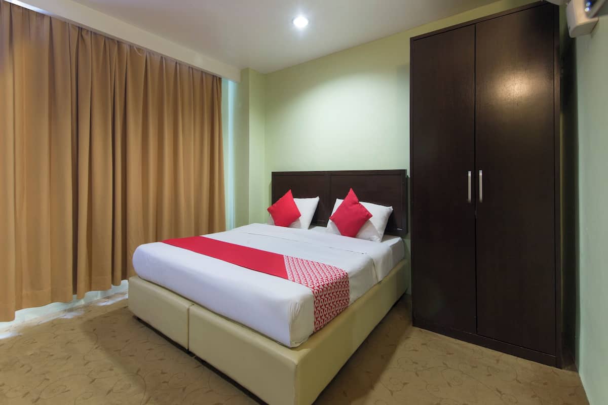A hotel room with a bed, a wardrobe, and a window with curtains.