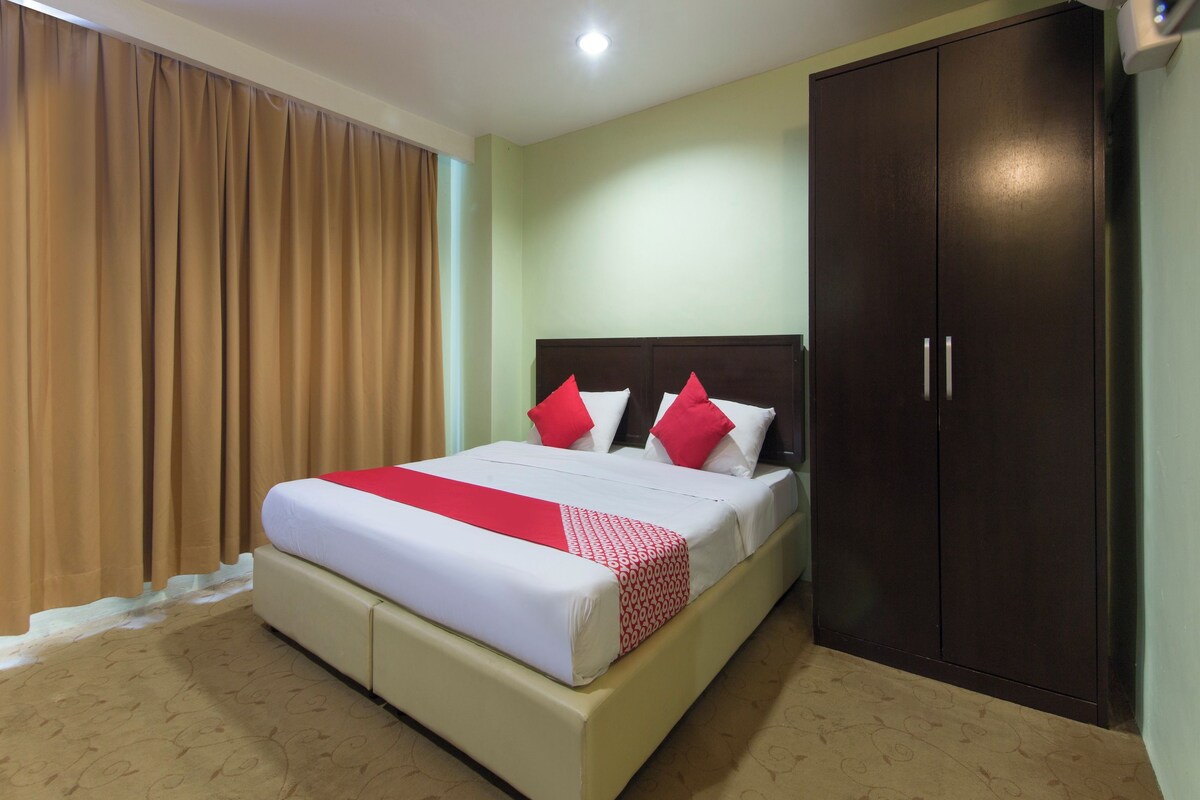 A hotel room with a bed, a wardrobe, and a window with curtains.