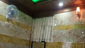 A hotel room with a bed, a fan, a mirror, and a red chair. - Hoa Anh Dao Garden Hotel (Ho Chi Minh City)