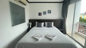 A hotel room with a large bed, a window with curtains, and a view of the outside. - Fruit Paradise Hotel (Patong)