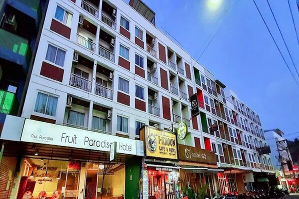 A multi-story hotel with balconies, a fruit store, and a cafe. - Fruit Paradise Hotel (Patong)
